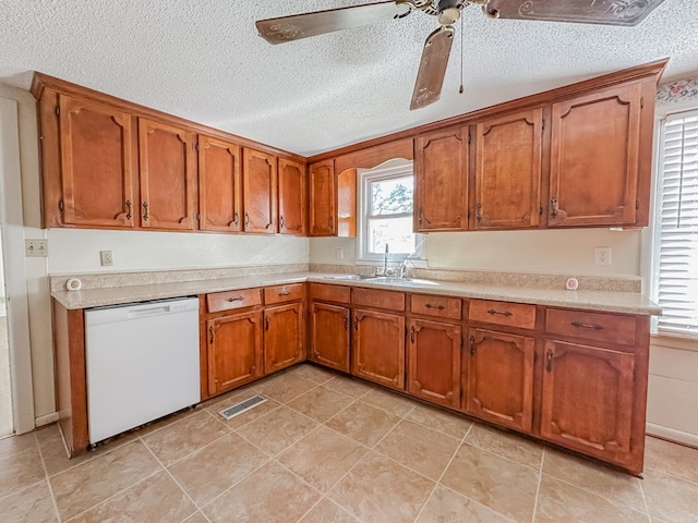 kitchen featuring brown cabinetry, visible vents, dishwasher, and a sink