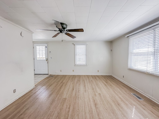 unfurnished living room featuring light wood finished floors, baseboards, visible vents, ceiling fan, and crown molding