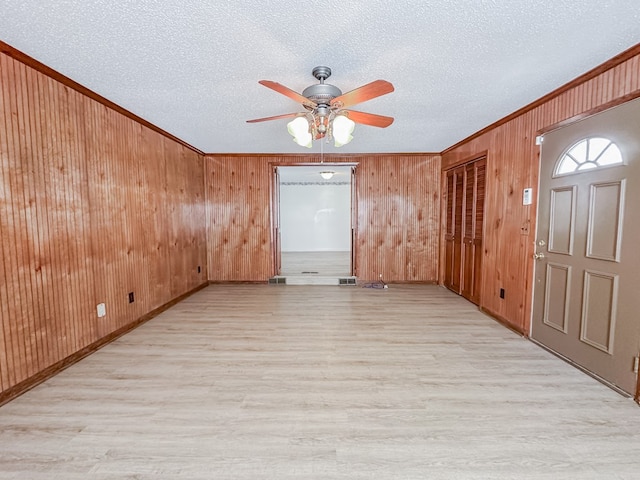 unfurnished room featuring light wood finished floors, ornamental molding, and a textured ceiling