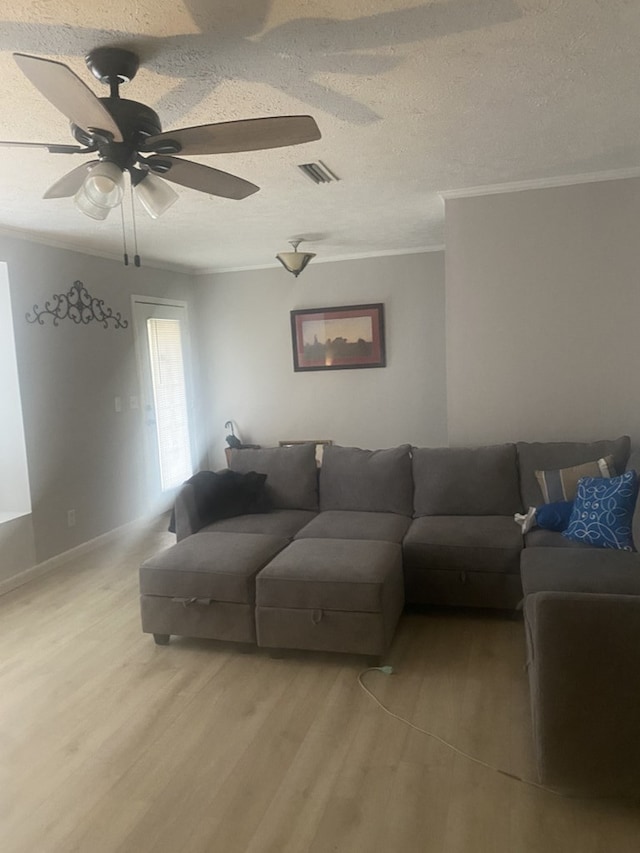 living room with crown molding, hardwood / wood-style floors, ceiling fan, and a textured ceiling