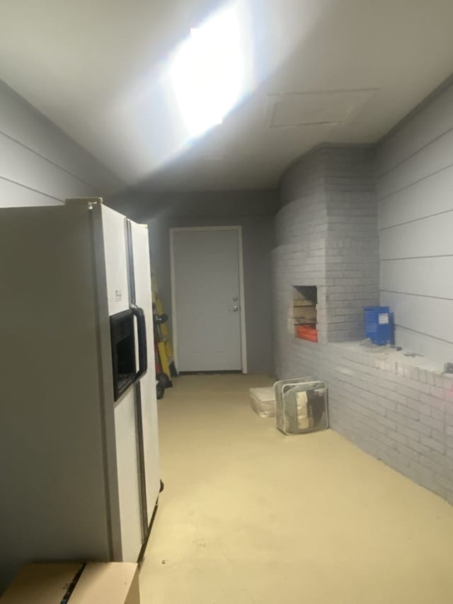 interior space with white fridge with ice dispenser and brick wall