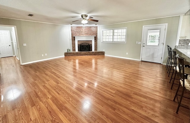 1006 Northfield Cir, Dothan, AL 36301 - unfurnished living room featuring ceiling fan, crown molding, a brick fireplace, light wood finished floors, and baseboards