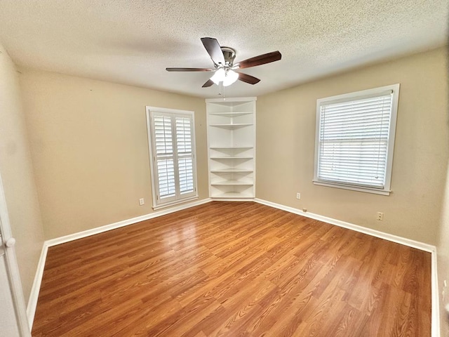 1006 Northfield Cir, Dothan, AL 36301 - empty room with light wood finished floors, baseboards, a textured ceiling, a ceiling fan, and built in shelves