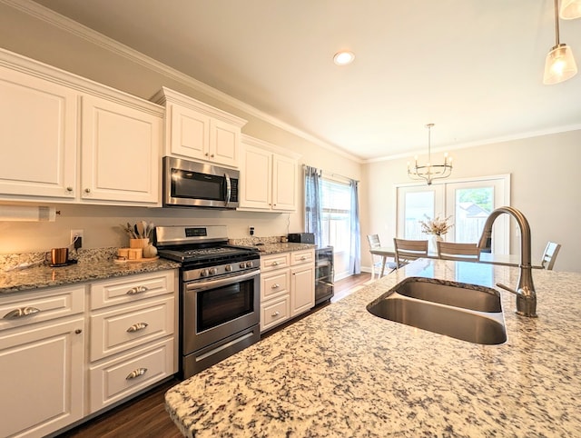 kitchen featuring dark wood-type flooring, white cabinets, hanging light fixtures, and appliances with stainless steel finishes