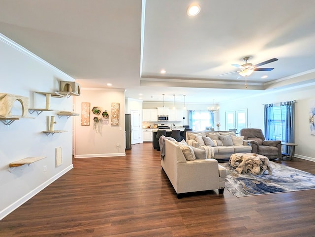 living room featuring ceiling fan with notable chandelier, dark hardwood / wood-style floors, and ornamental molding