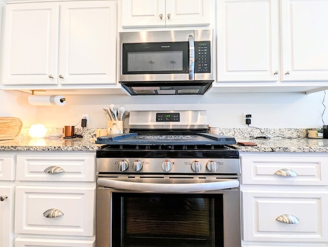 kitchen with white cabinets, appliances with stainless steel finishes, and light stone countertops