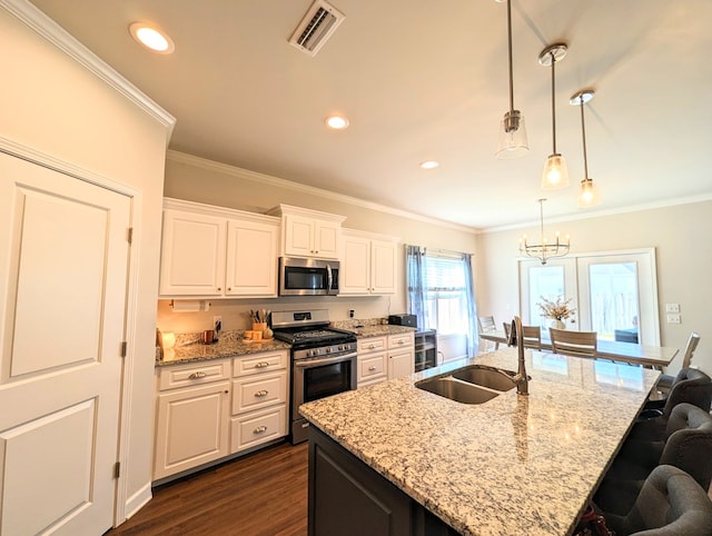 kitchen with sink, an island with sink, pendant lighting, white cabinets, and appliances with stainless steel finishes