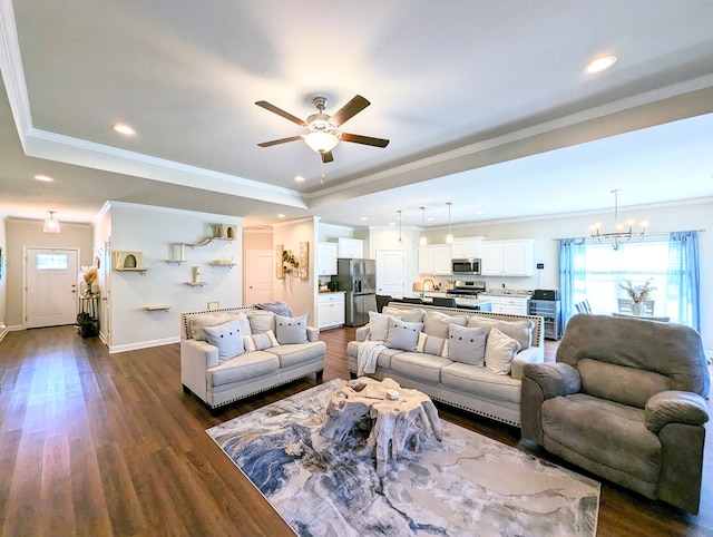 living room featuring a raised ceiling, ceiling fan with notable chandelier, dark hardwood / wood-style flooring, and crown molding