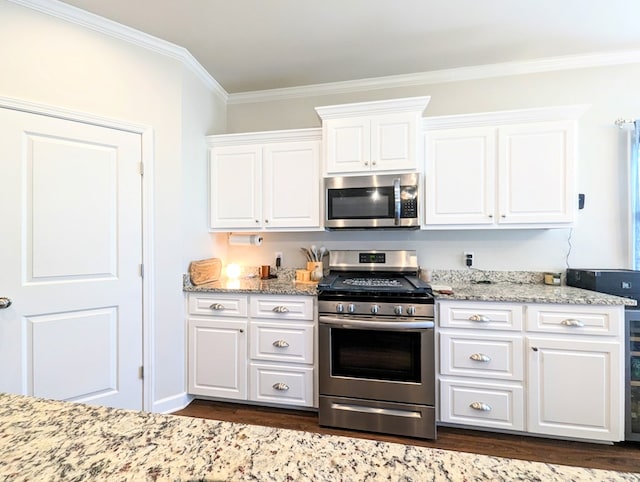 kitchen with appliances with stainless steel finishes, dark hardwood / wood-style flooring, white cabinetry, and ornamental molding