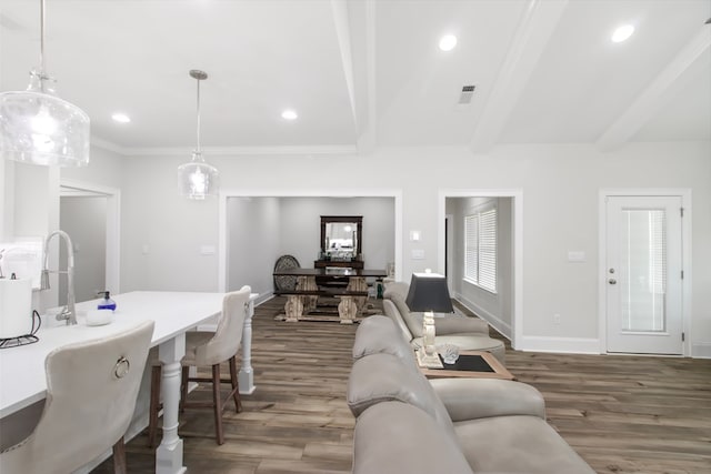 living room featuring beamed ceiling, crown molding, and dark wood-type flooring