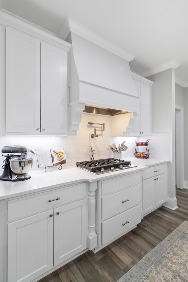 bar featuring premium range hood, stainless steel gas cooktop, ornamental molding, white cabinets, and backsplash