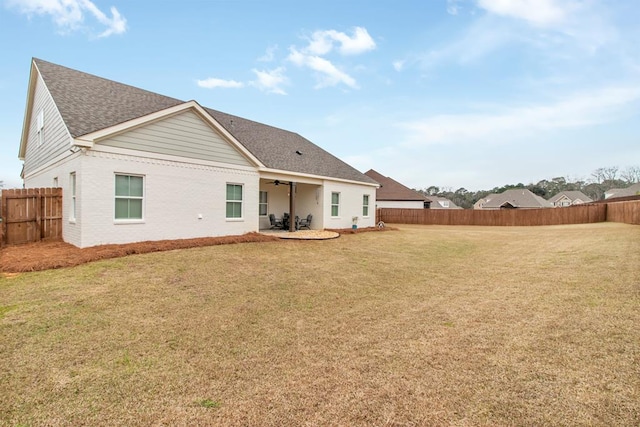 back of property with ceiling fan and a yard