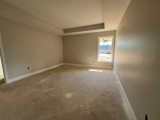 empty room with a tray ceiling and concrete flooring