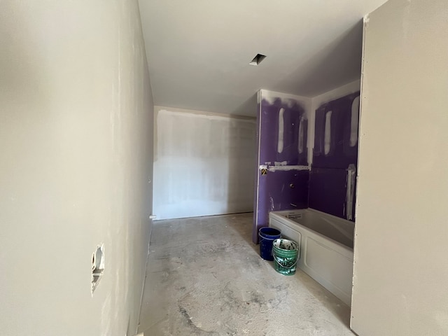 bathroom with a bathtub and concrete floors