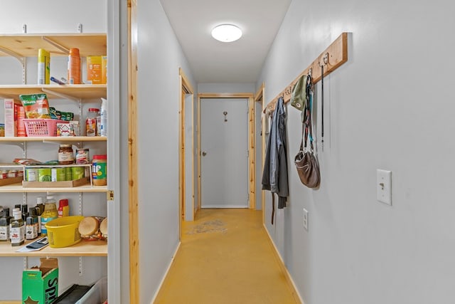 hall featuring baseboards and concrete flooring