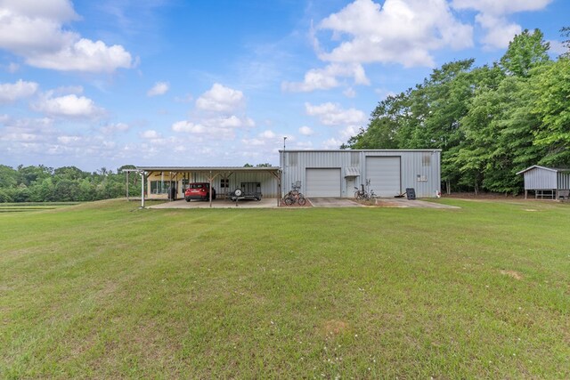 rear view of property featuring an outdoor structure, a lawn, and a detached garage