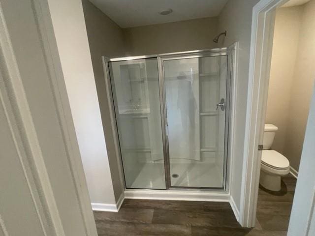 bathroom with hardwood / wood-style floors, toilet, and a shower with shower door