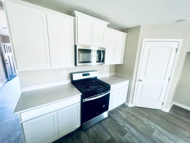 kitchen featuring white cabinets, appliances with stainless steel finishes, and dark hardwood / wood-style flooring