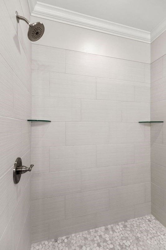 bathroom featuring ornamental molding and tiled shower