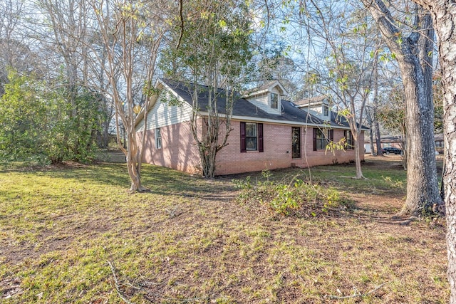 view of property exterior with brick siding and a yard