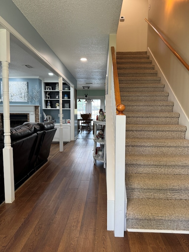 stairs featuring built in shelves, a textured ceiling, and hardwood / wood-style flooring