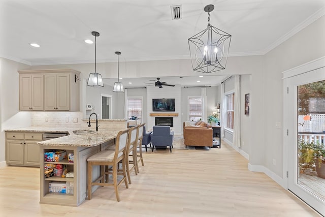 kitchen featuring sink, decorative light fixtures, backsplash, and light stone counters