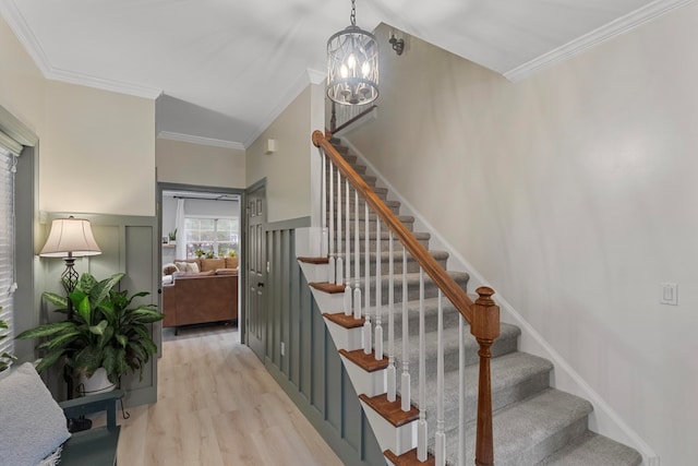 stairway featuring an inviting chandelier, crown molding, and wood-type flooring