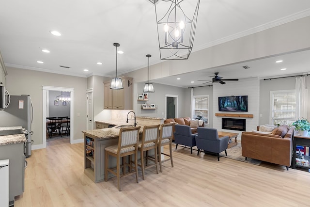 kitchen with light stone countertops, light hardwood / wood-style flooring, hanging light fixtures, stainless steel appliances, and a breakfast bar