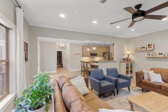 living room featuring ornamental molding, light wood-type flooring, and ceiling fan with notable chandelier