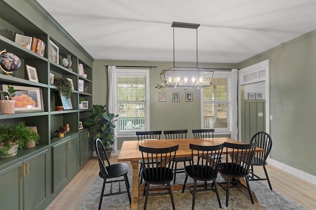 dining space featuring an inviting chandelier, light wood-type flooring, and crown molding