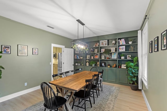 dining space featuring light hardwood / wood-style floors and a chandelier