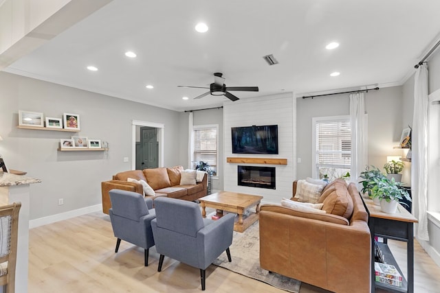 living room with a healthy amount of sunlight, ceiling fan, light wood-type flooring, and a fireplace