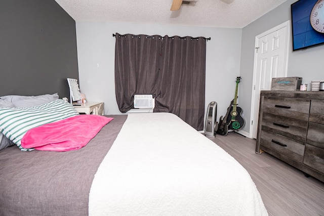 52 Oakwood Dr, Midland City, AL 36350 - bedroom featuring light wood finished floors, a textured ceiling, cooling unit, and a ceiling fan
