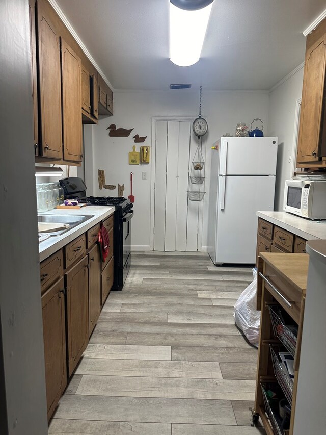 1712 Sowell Rd, Brewton, AL 36426 - kitchen with sink, light wood-type flooring, white appliances, and ornamental molding
