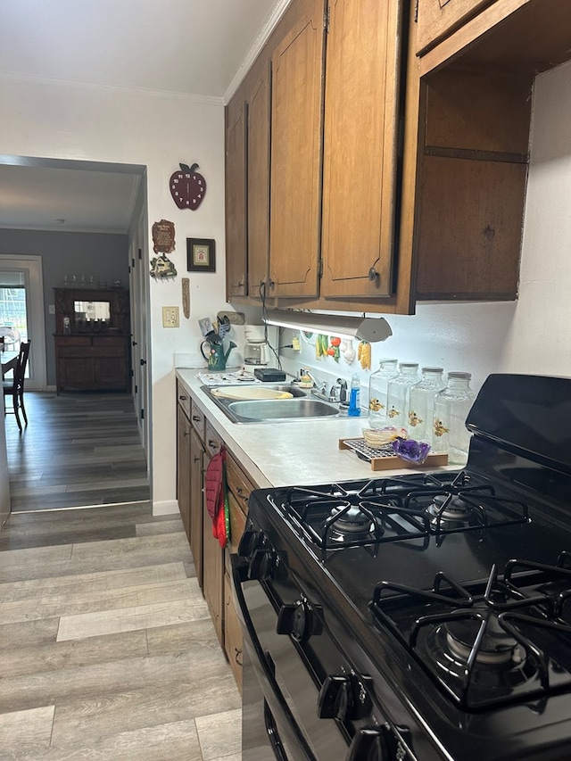 1712 Sowell Rd, Brewton, AL 36426 - kitchen featuring black gas range, light hardwood / wood-style flooring, ornamental molding, and sink
