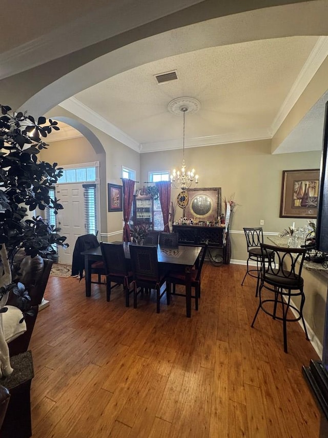 dining space featuring crown molding, hardwood / wood-style flooring, plenty of natural light, and a chandelier