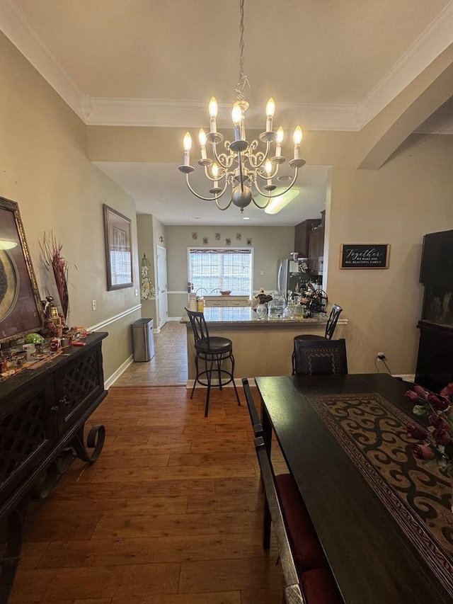 dining space with an inviting chandelier, ornamental molding, and wood-type flooring