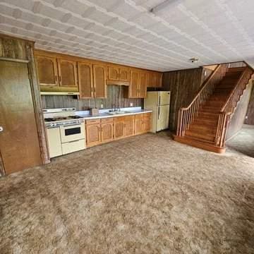 8159 State Highway 10, Shorterville, AL 36373 - kitchen with carpet, under cabinet range hood, light countertops, brown cabinetry, and white appliances