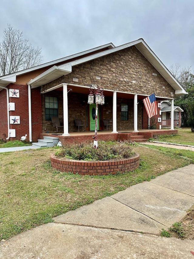 view of front of home featuring a front lawn, a porch, and brick siding