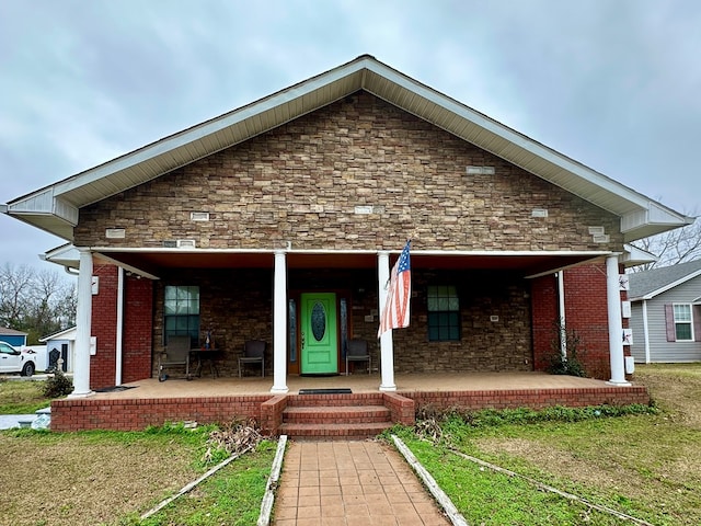 view of front of property with covered porch, stone siding, and brick siding