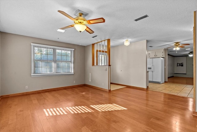 unfurnished living room with ceiling fan, a textured ceiling, and light wood-type flooring