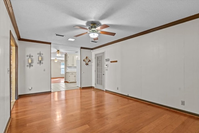 empty room featuring light wood-type flooring, a textured ceiling, and ornamental molding