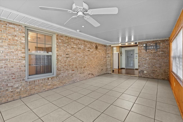 interior space with ceiling fan and brick wall