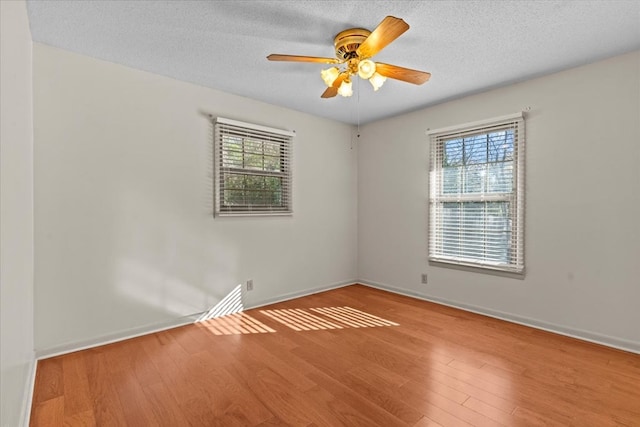 empty room with ceiling fan, light hardwood / wood-style flooring, and a textured ceiling