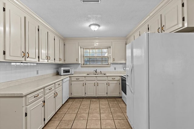 kitchen with light tile patterned floors, white appliances, white cabinetry, and sink