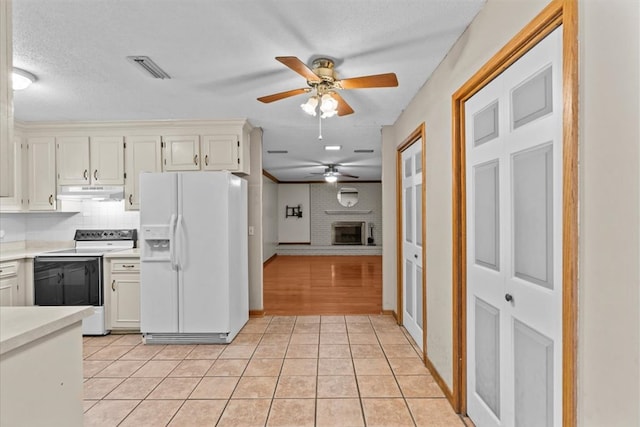 kitchen featuring decorative backsplash, white appliances, a fireplace, and light tile patterned floors