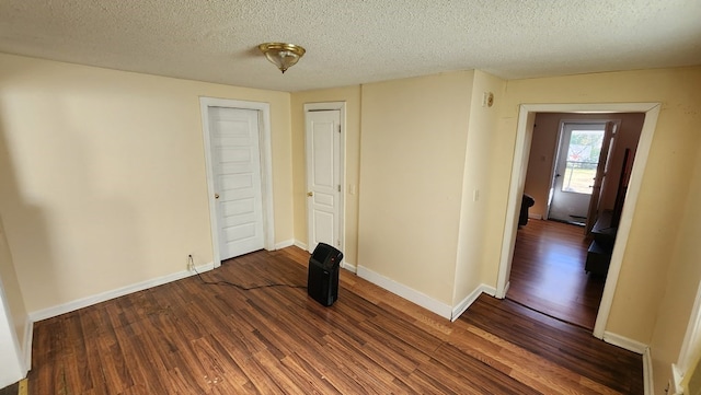 unfurnished room with a textured ceiling and dark hardwood / wood-style floors