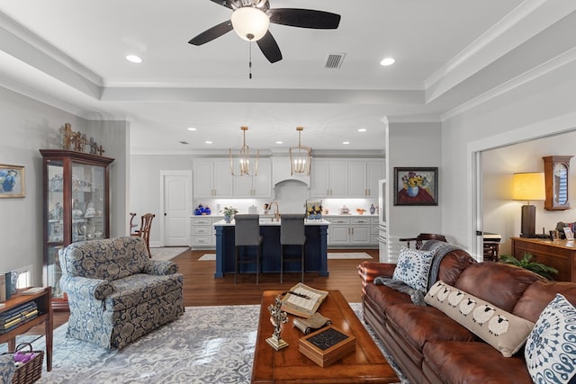 living room with dark hardwood / wood-style flooring, a raised ceiling, ceiling fan, and crown molding