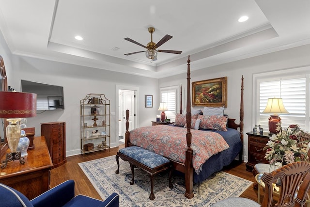 bedroom with dark wood-type flooring, a raised ceiling, and crown molding