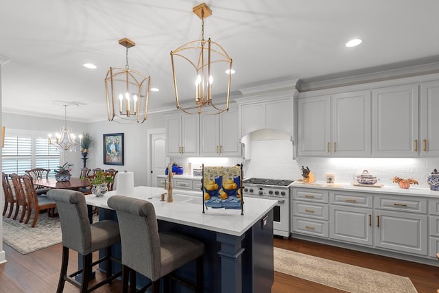 kitchen featuring a notable chandelier, a kitchen island with sink, decorative light fixtures, crown molding, and high end stove